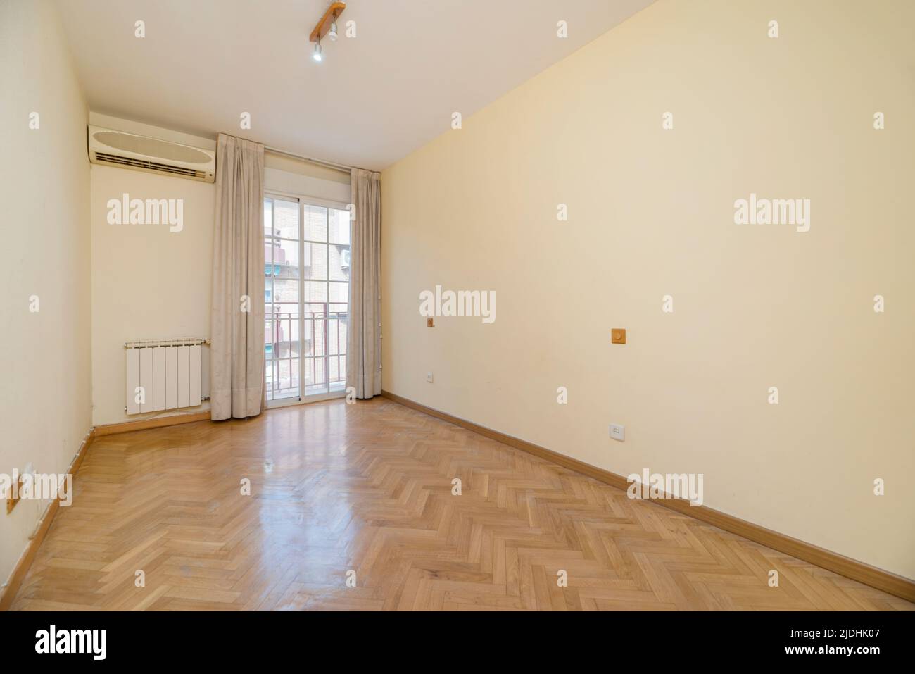 Empty room with balcony with white curtains and aluminum and glass sliding doors, aluminum radiator and air conditioner Stock Photo