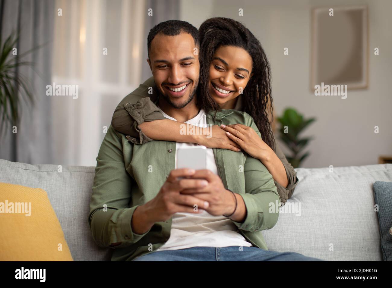 Happy African American Couple Using Mobile Phone At Home Stock Photo