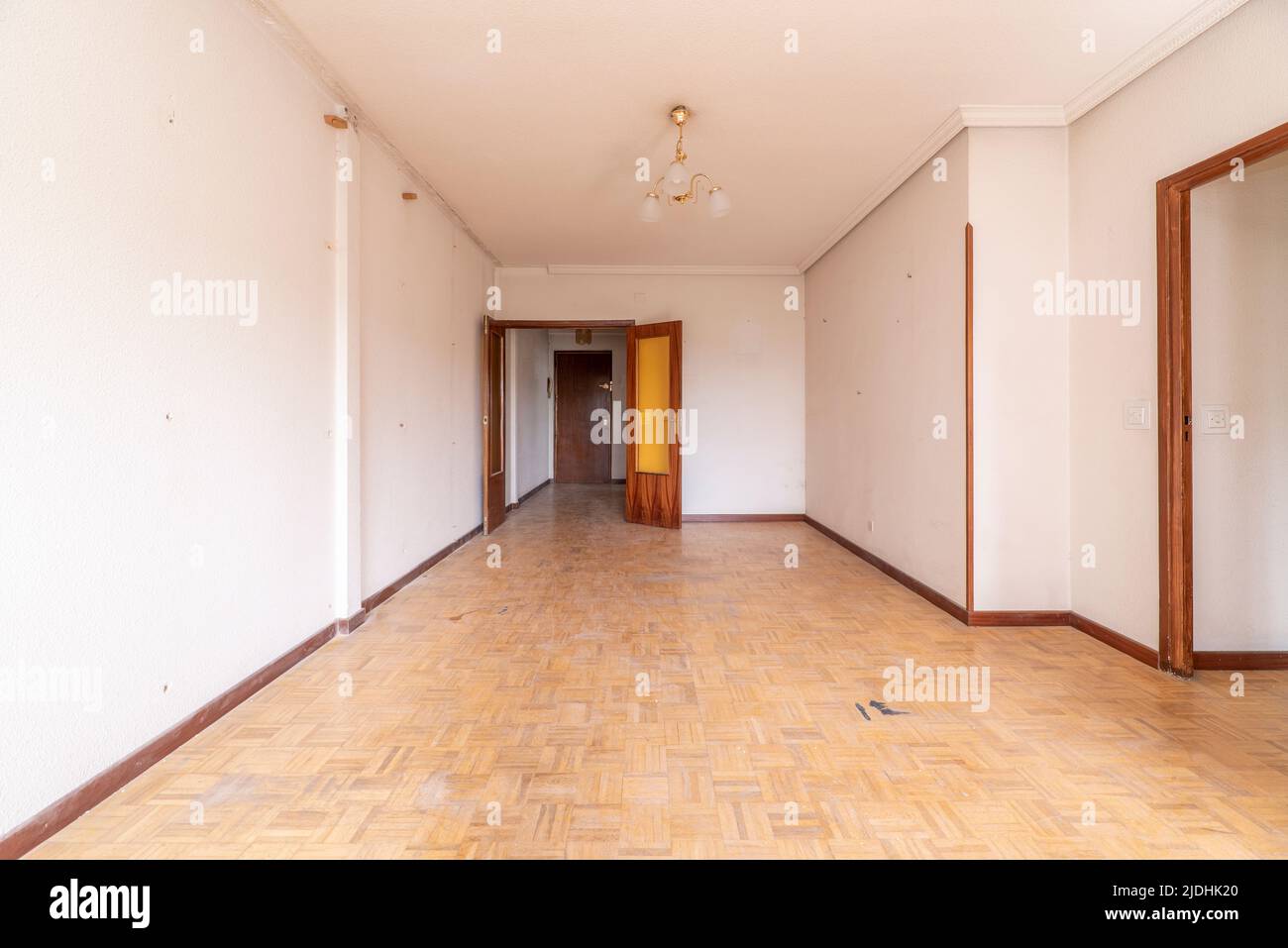 Empty room with parquet floors in need of a coat of varnish, wood carpentry and orange glass on the doors Stock Photo