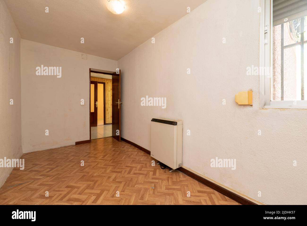 Empty room with oak parquet floor and wood carpentry on doors and heat accumulator on the wall Stock Photo