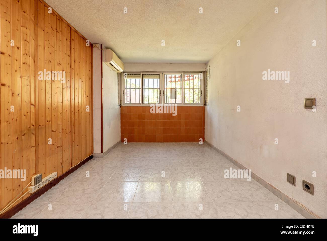Empty room with aluminum windows and air conditioning with ceramic floors and a wall with brown tiles Stock Photo
