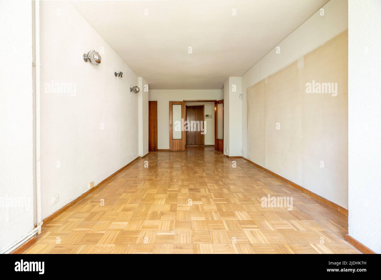 Empty room with oak parquet flooring, white painted walls and dark woodwork Stock Photo