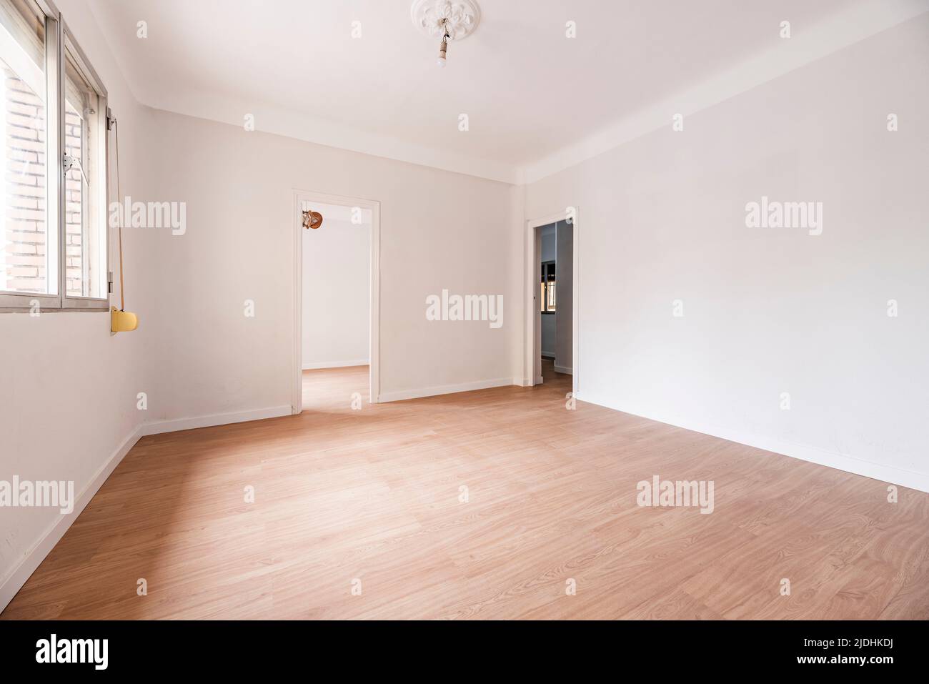 Empty room with oak parquet floor, white painted walls and white woodwork and plaster moldings on the ceiling Stock Photo