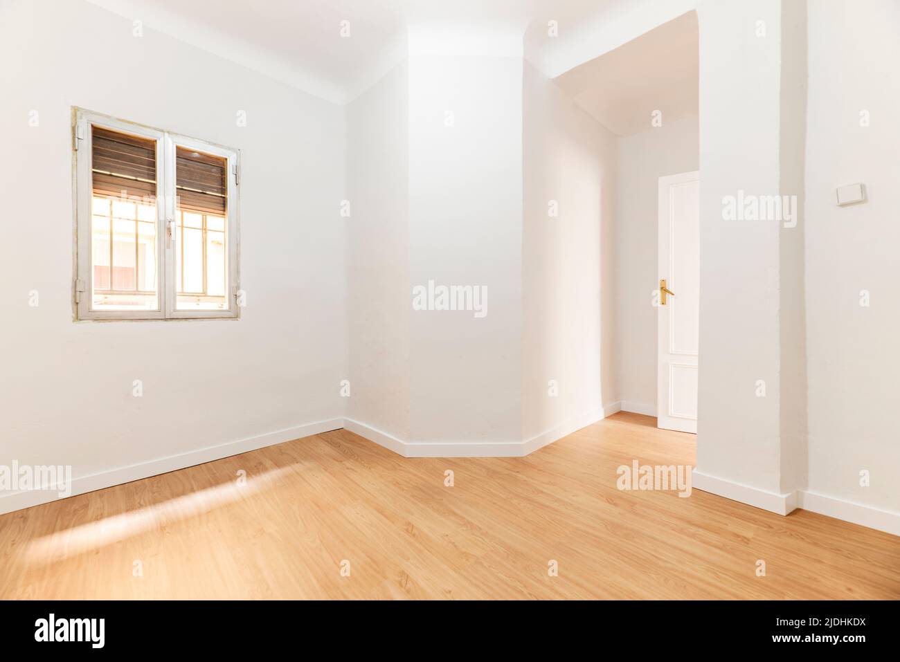 Empty room with oak parquet floor, white painted walls and aluminum windows Stock Photo