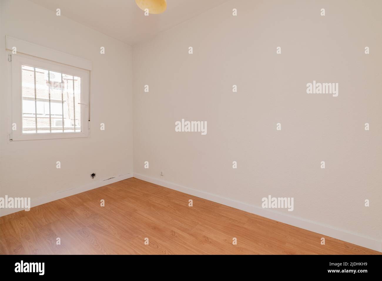 Empty room with oak parquet floor, white painted walls and white aluminum windows with a view Stock Photo