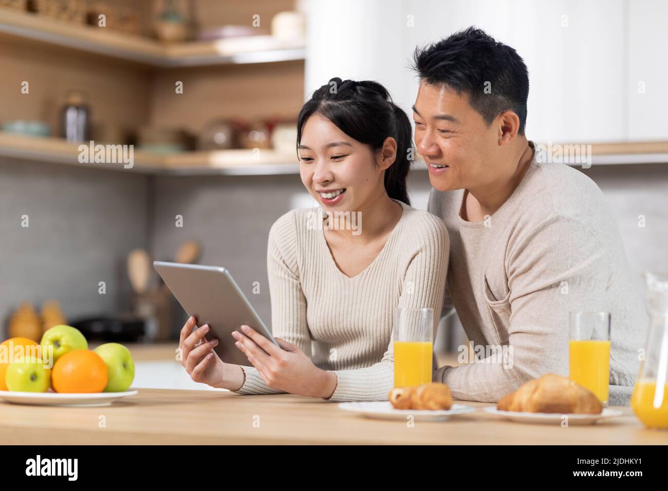Happy chinese family using digital tablet while having breakfast Stock Photo