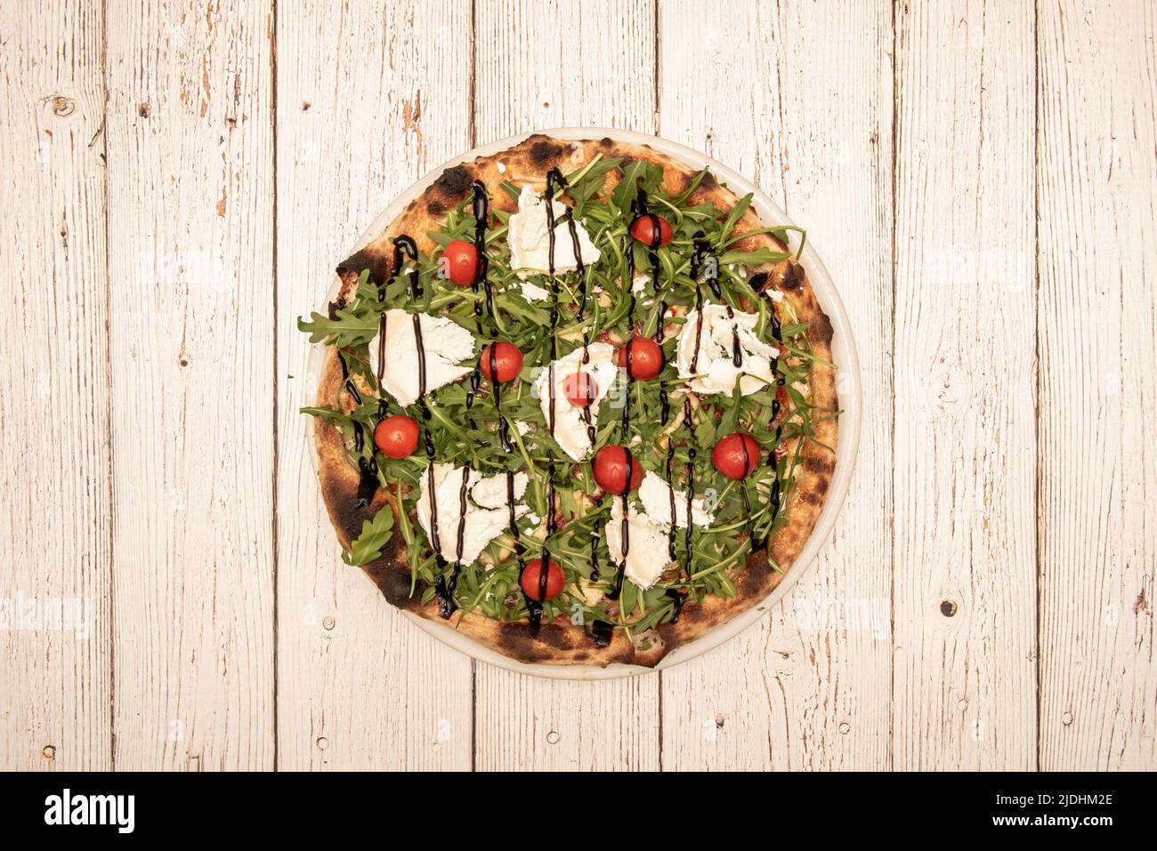 Top view image of pizza with arugula, goat cheese, cherry tomatoes and balsamic of modena Stock Photo