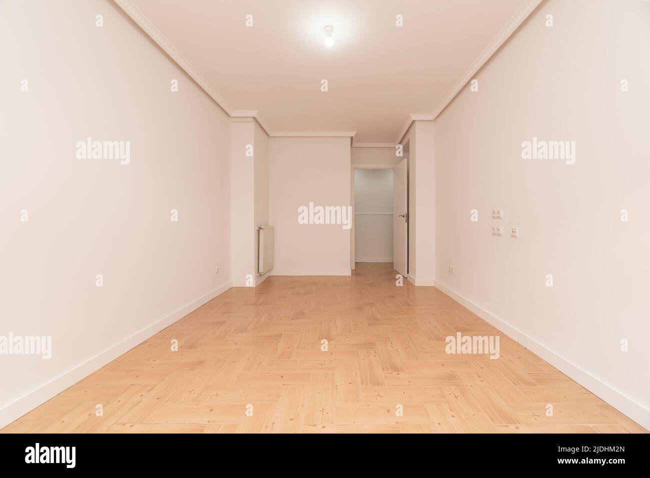 Empty room with wood-like stoneware floors, white painted walls and aluminum radiator Stock Photo