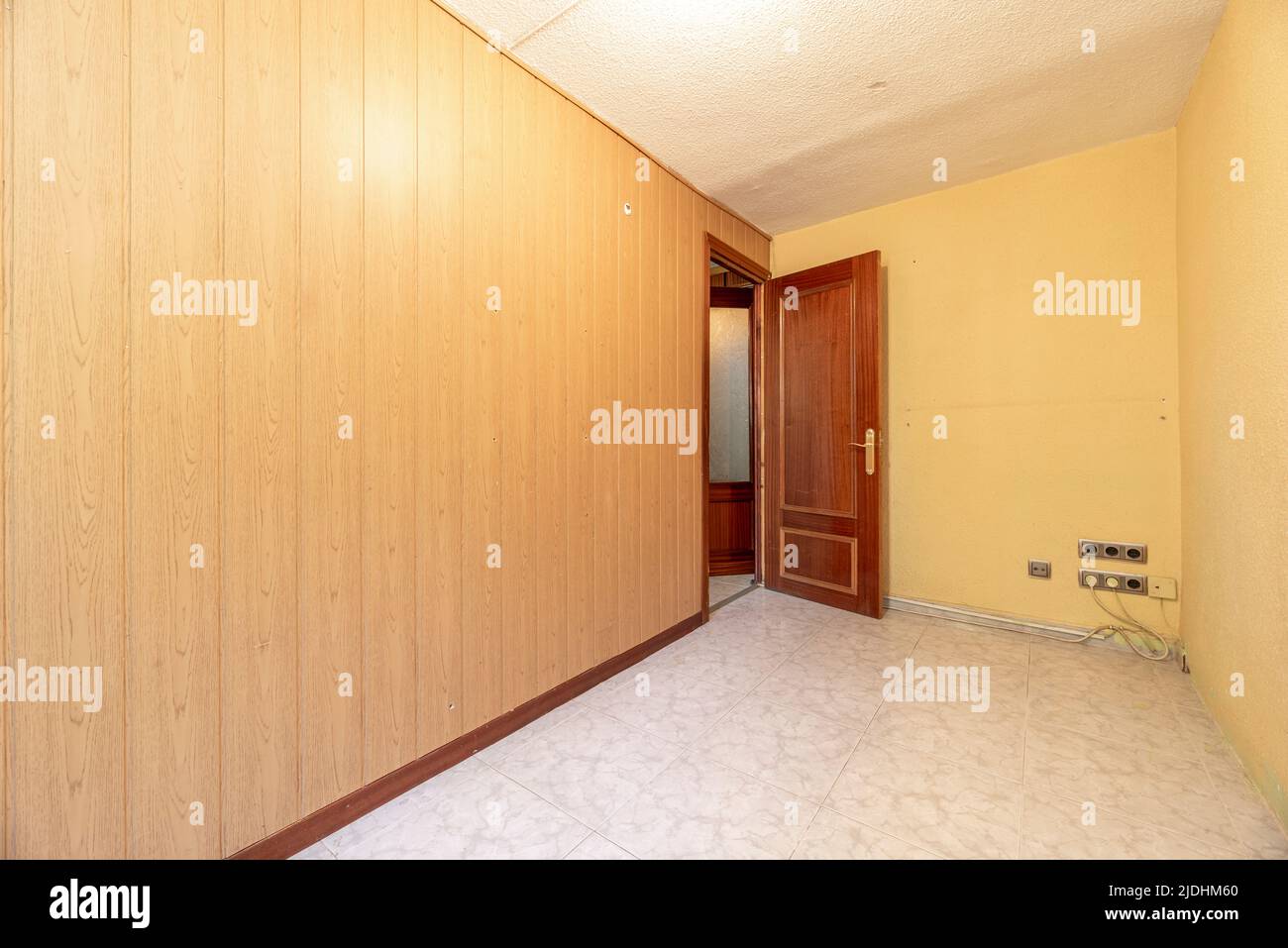 Empty room with wall covered in wood-like PVC tongue-and-groove and ceramic tile floors Stock Photo