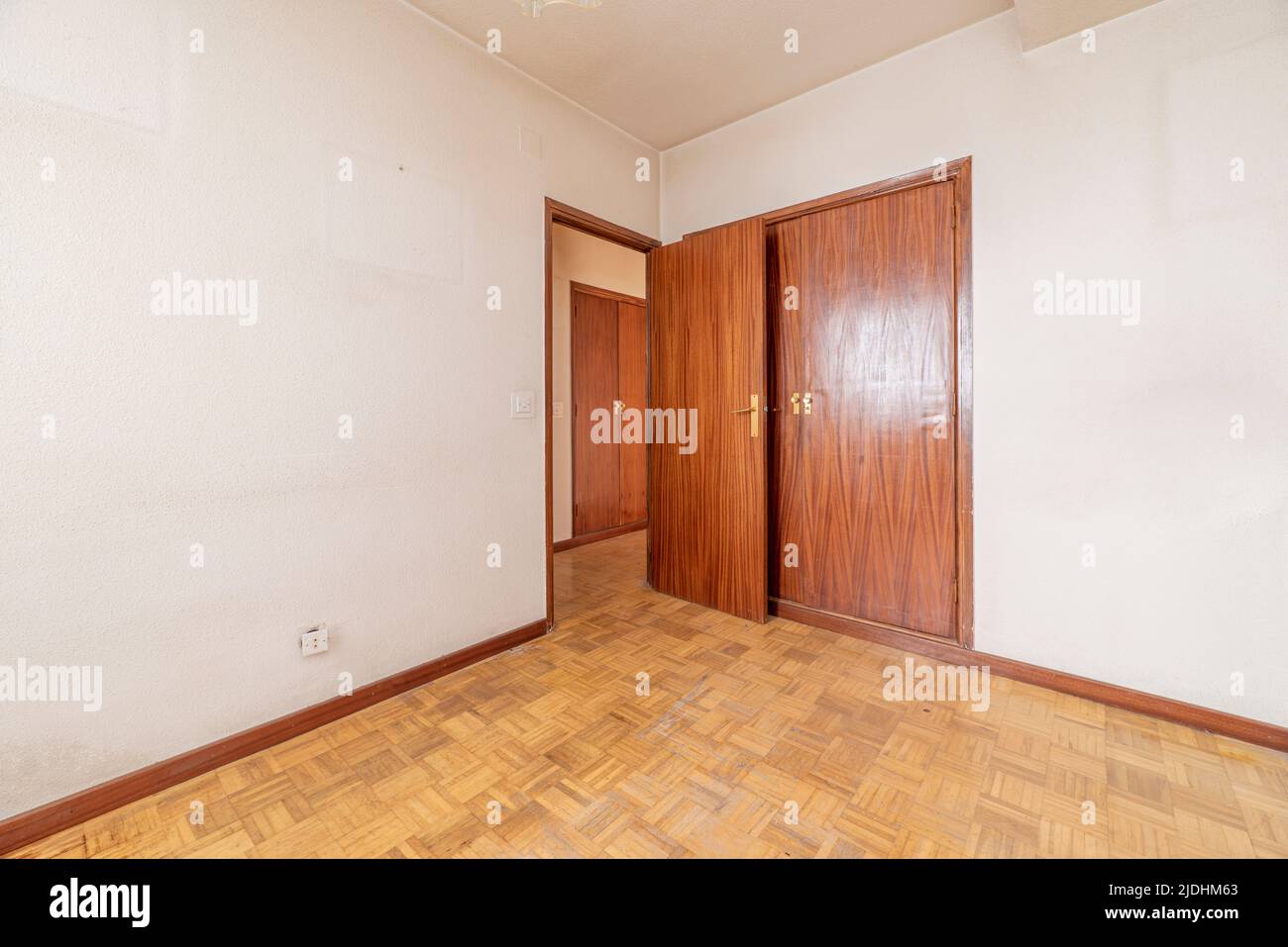 Empty room with plain white painted walls, built-in wardrobe with wooden doors to match the carpentry Stock Photo