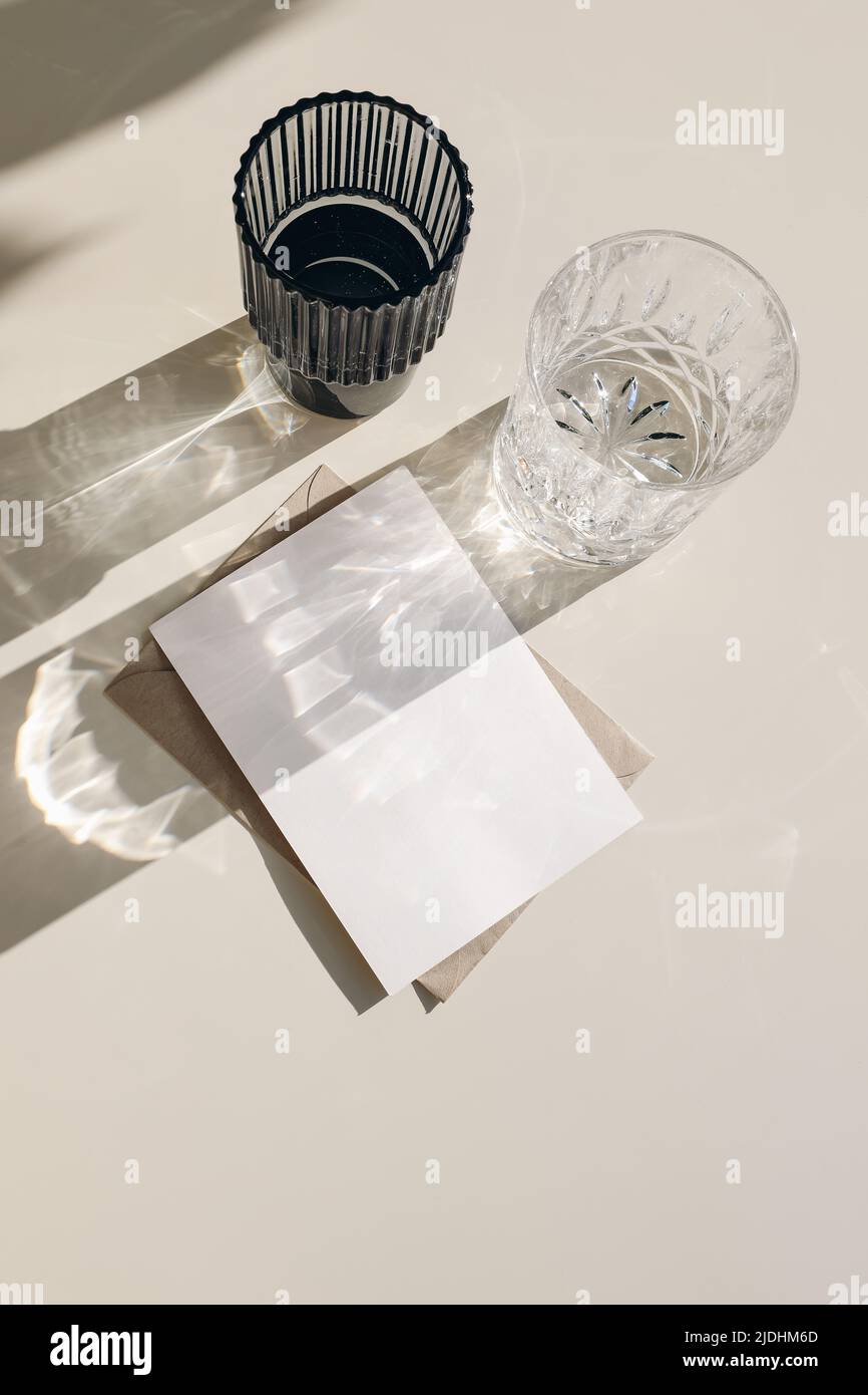 Modern summer drinks still life. Glasses of water, cocktails in sunlight. Long harsh shadows. Beige table background. Blank greeting card, envelope mo Stock Photo