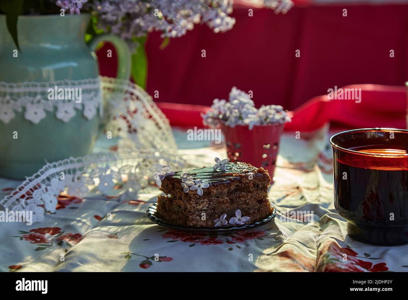 Moody homemade chocolate cake. Dessert and cup of coffee among flowers. Atmospheric breakfast.  Stock Photo