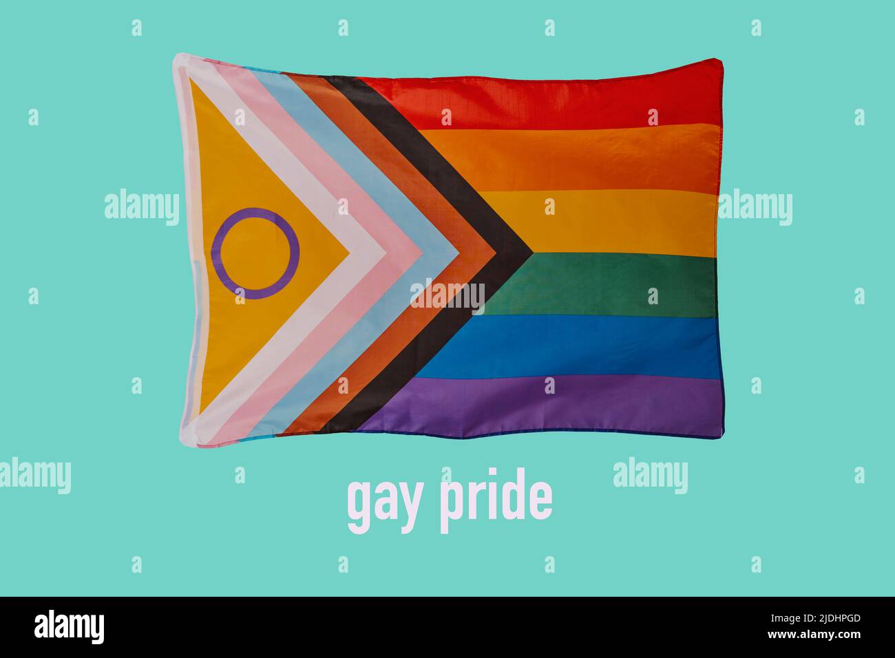 the text gay pride and an intersex-inclusive progress pride flag waving in the air on a greenish blue background Stock Photo