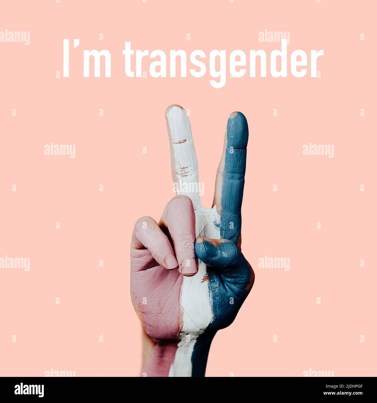 closeup of the hand of a person doing the V-sign with the transgender pride flag painted in it, and the text I am transgender on a salmon pink backgro Stock Photo
