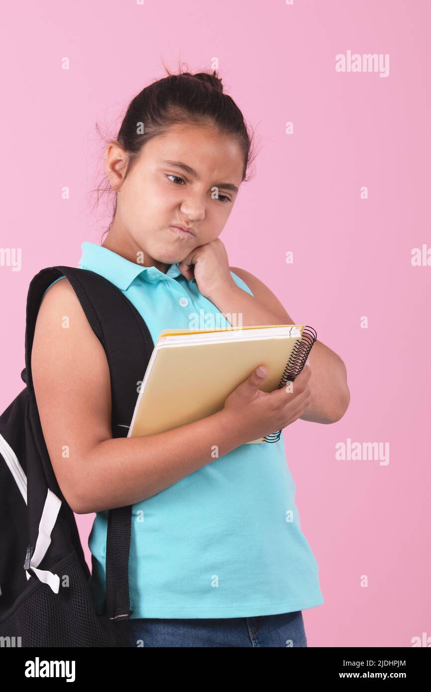School girl holding notebook and carrying backpack with angry
