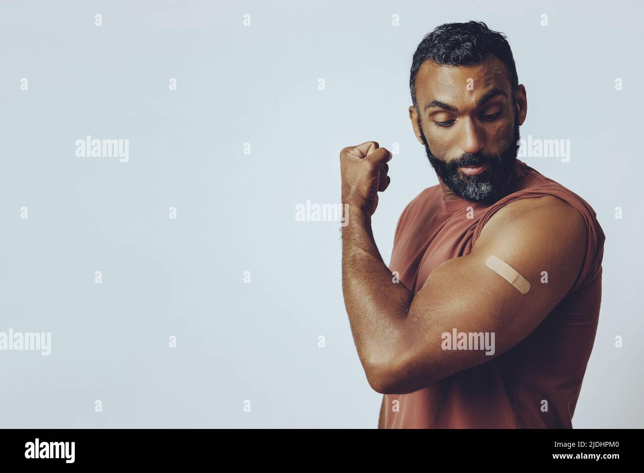 portrait mid adult bearded vaccinated man in the studio flexing arm muscle with plaster studio shot Stock Photo