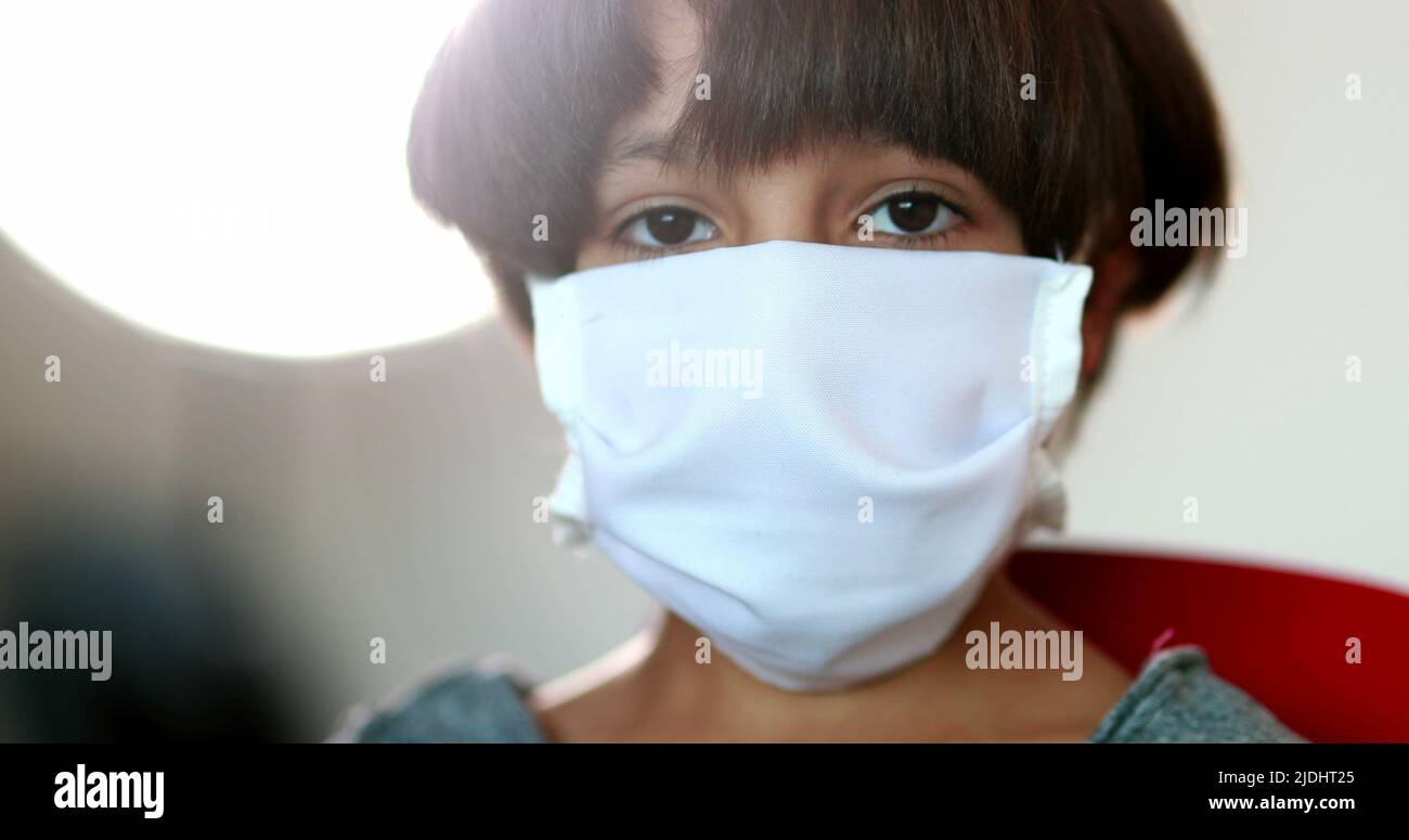 Young boy putting pandemic mask prevention on face, kid wearing