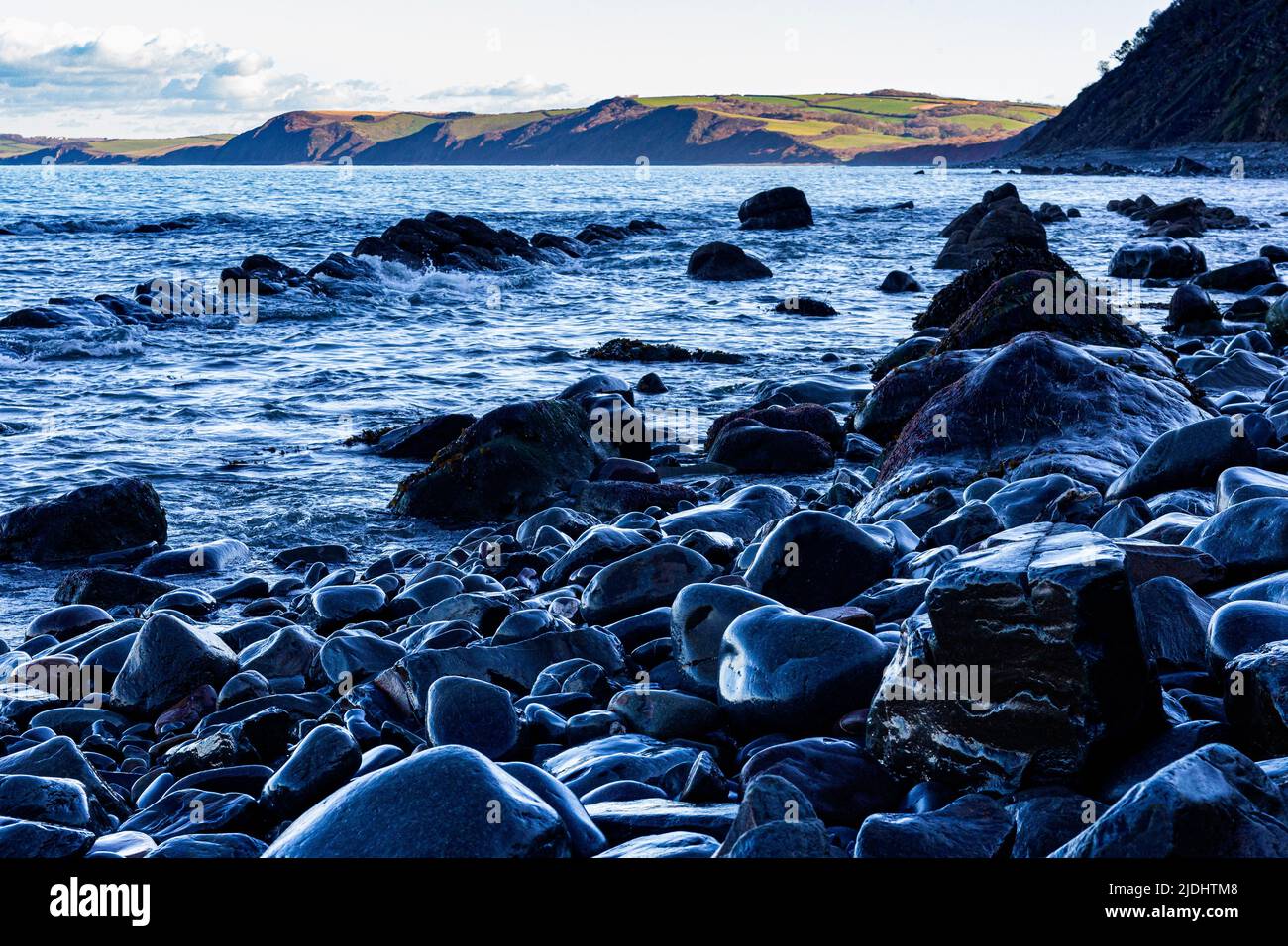 Colourful Moody Light on Wet Rocks, Bucks Mills Beach at High Tide with View of the Beach and North Devon Coastline,  Bucks Mills, Devon, Stock Photo