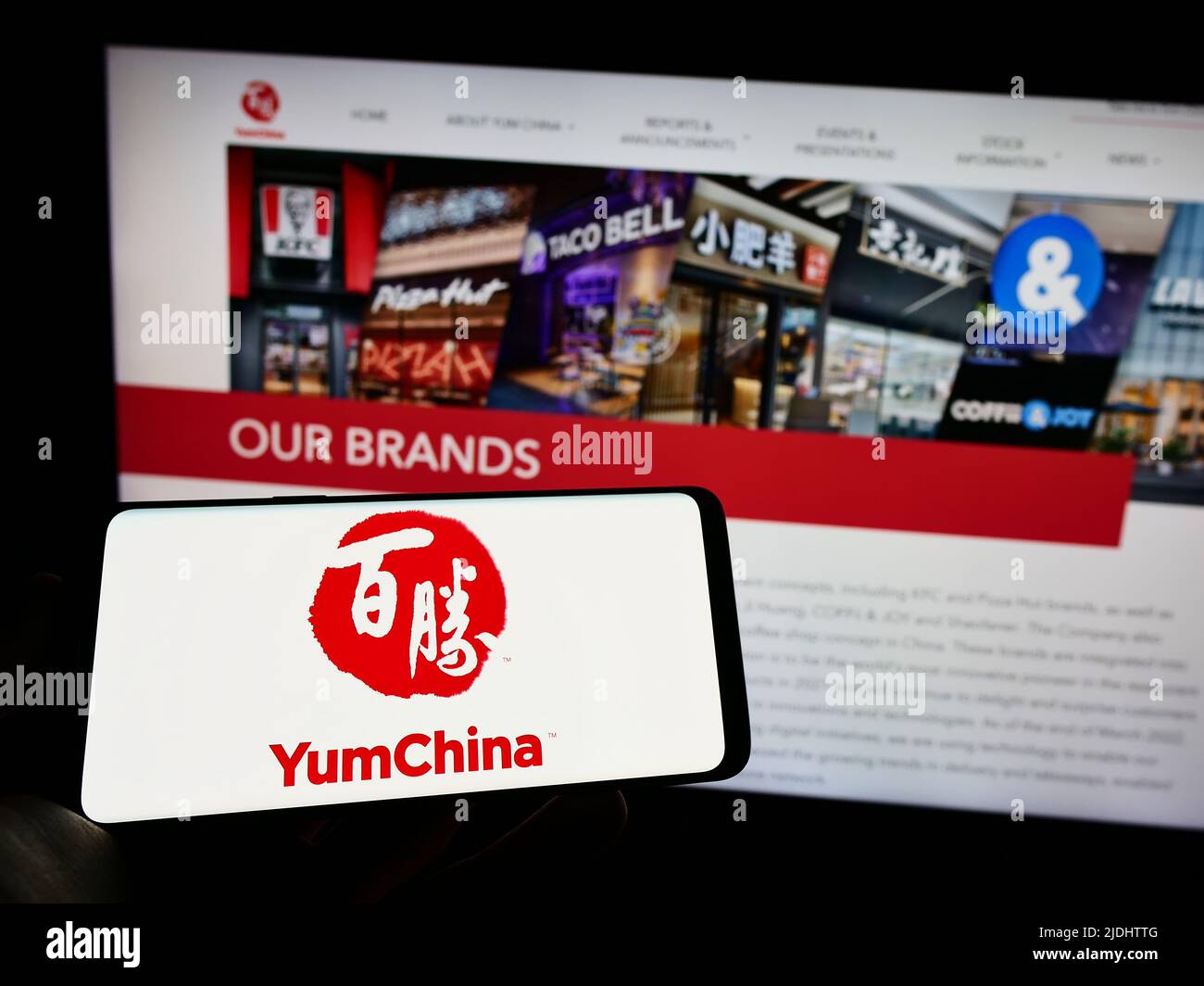 Person holding cellphone with logo of restaurant company Yum China Holdings Inc. on screen in front of business webpage. Focus on phone display. Stock Photo