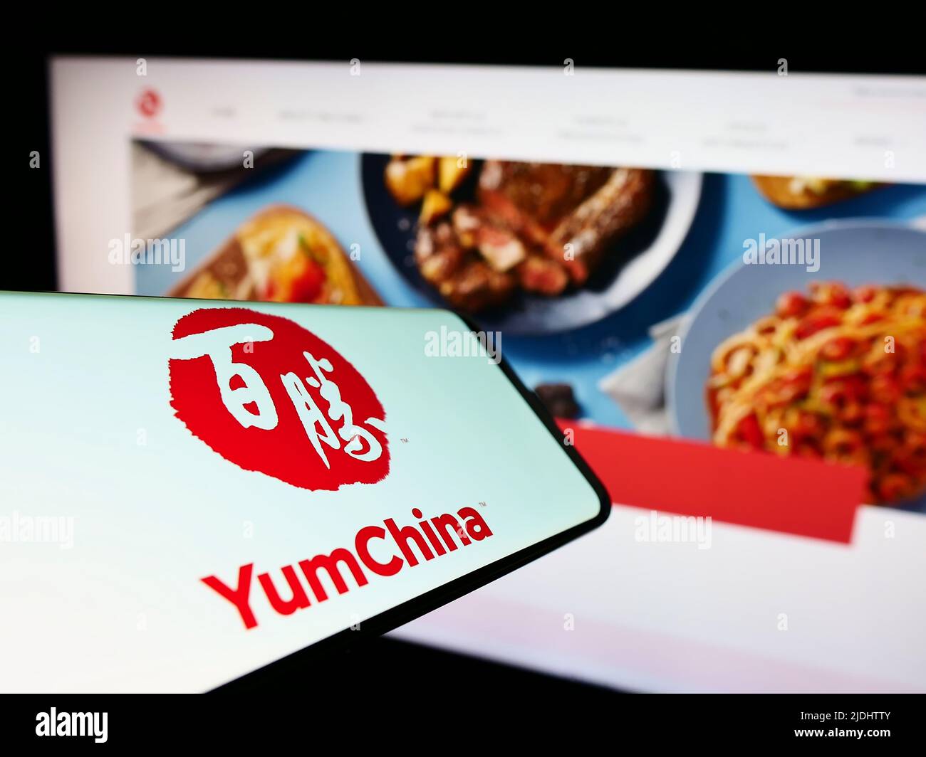 Smartphone with logo of restaurant company Yum China Holdings Inc. on screen in front of business website. Focus on center-right of phone display. Stock Photo