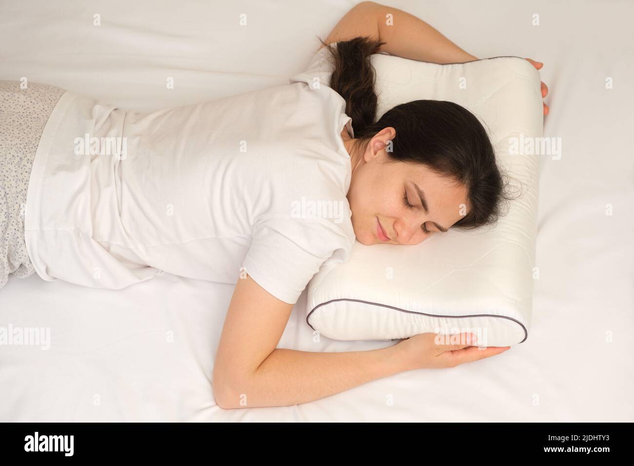 https://c8.alamy.com/comp/2JDHTY3/a-woman-sleeps-on-her-stomach-on-an-orthopedic-pillow-made-of-memory-foam-2JDHTY3.jpg