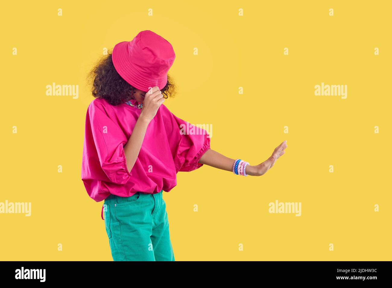 African American child in pink bucket hat doing moonwalk isolated on yellow background Stock Photo
