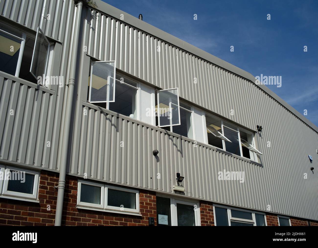 Office windows open in an industrial unit office complex on a hot sunny day. Stock Photo