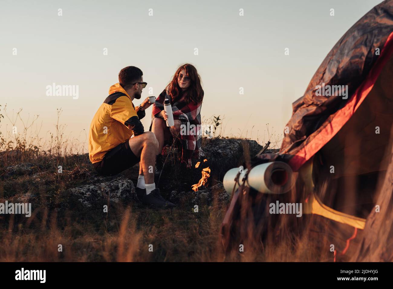 Two Young Travelers Man and Woman Sitting Near the Campfire and Tent ...
