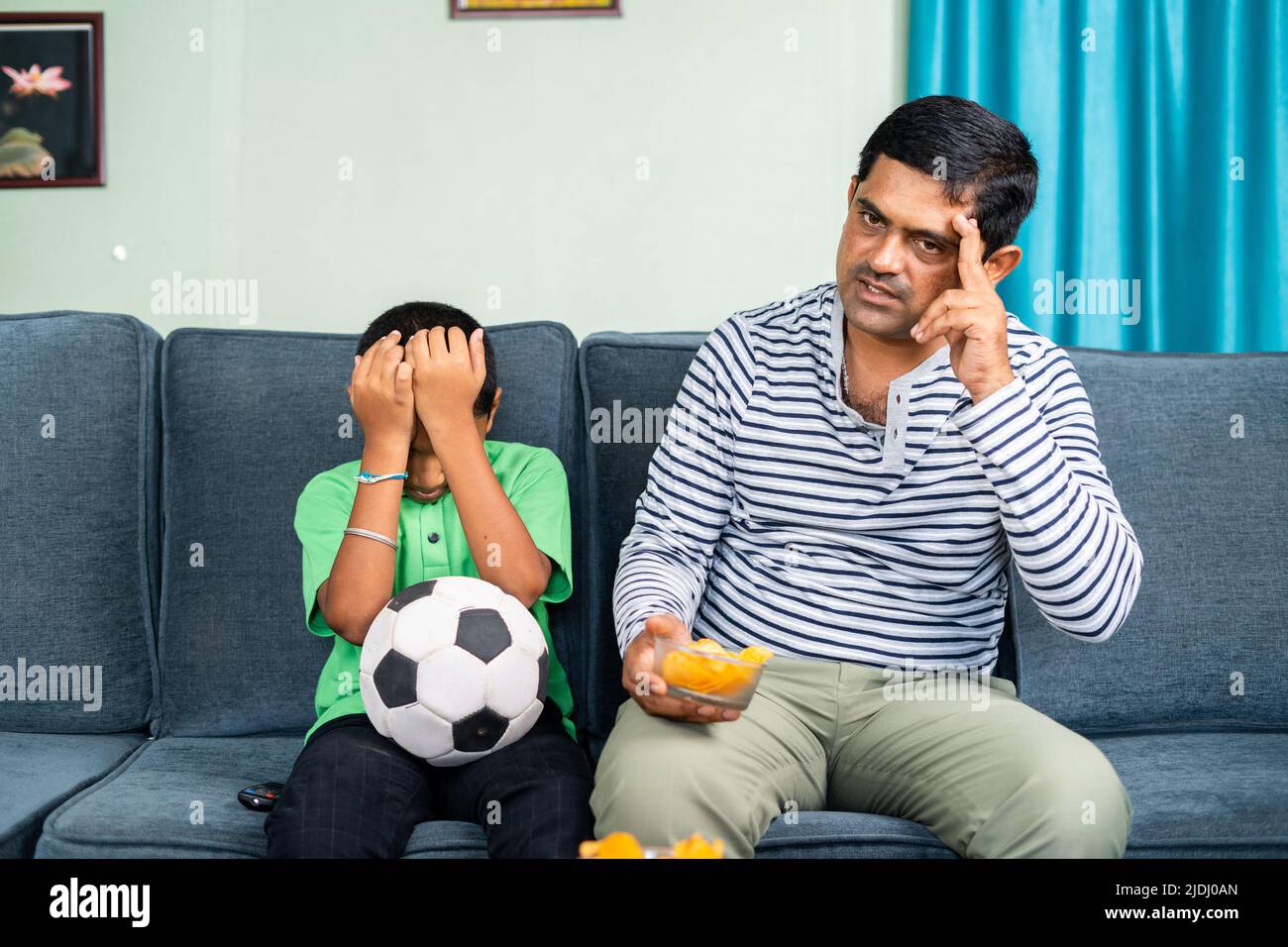 father and son got sad while live football game at home on sofa - concept of entertainment, depressed and supporters Stock Photo