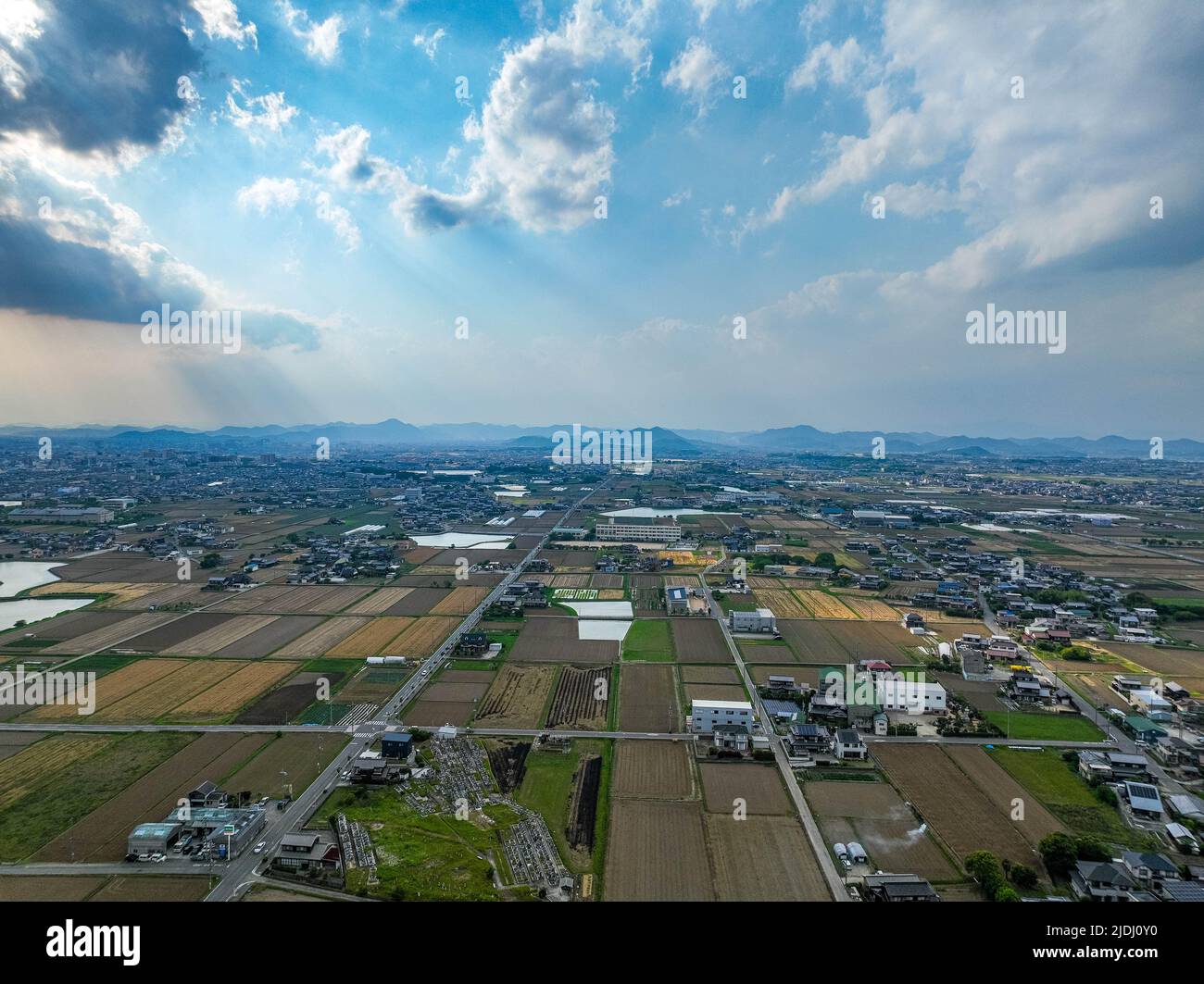 Dramatic clouds and sun rays shine over rural farming area Stock Photo