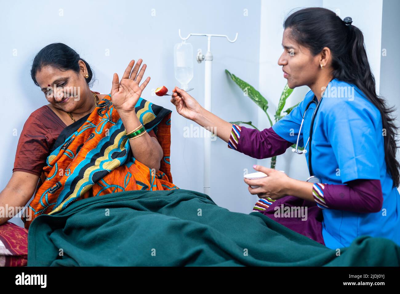 sick middle aged patient saying no to eat fruits from caring nurse at hospital nursing home - concept of caring, assistant and professional occupation Stock Photo