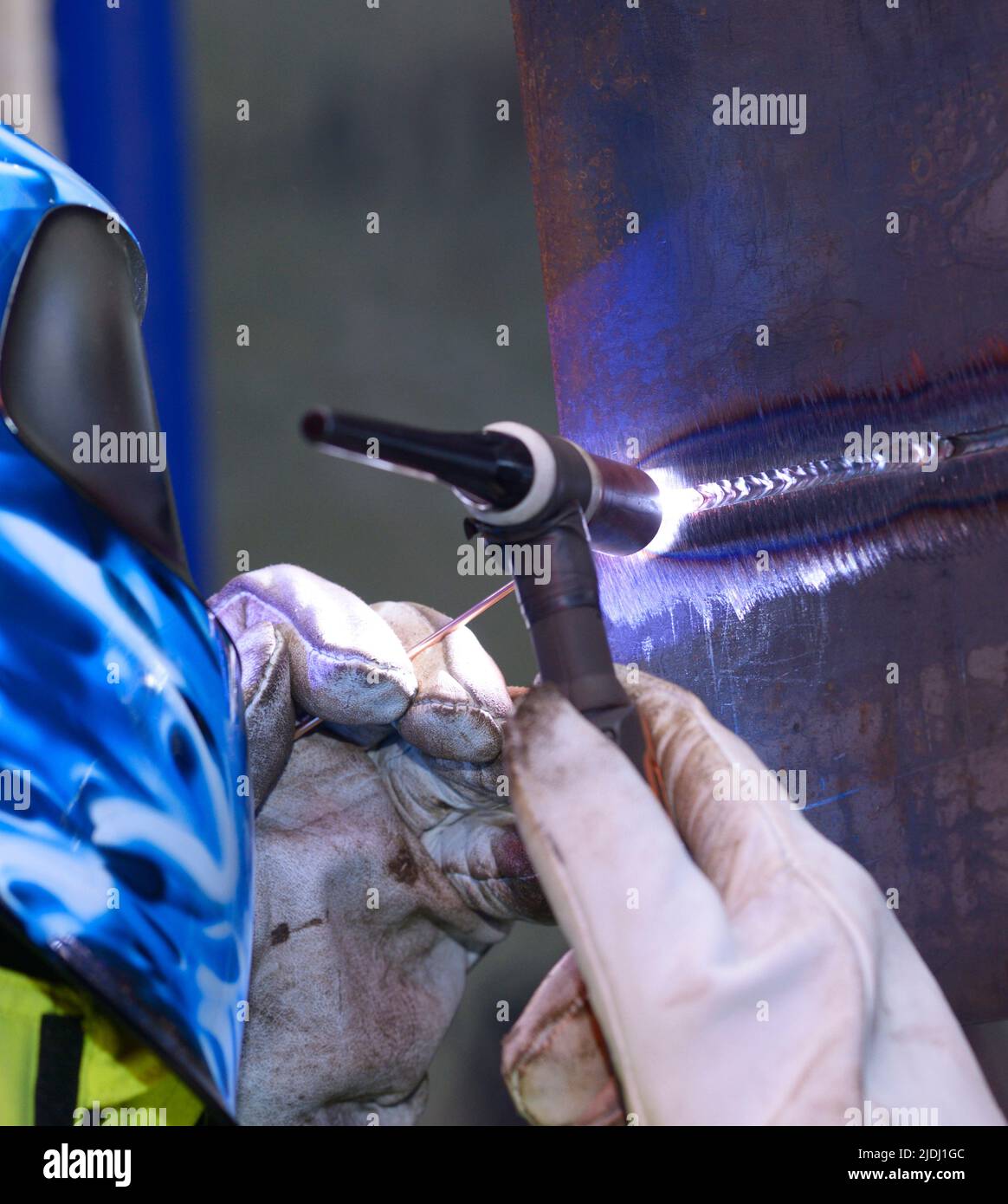 welder hands weld two pieces of metal using argon torch and filler rod