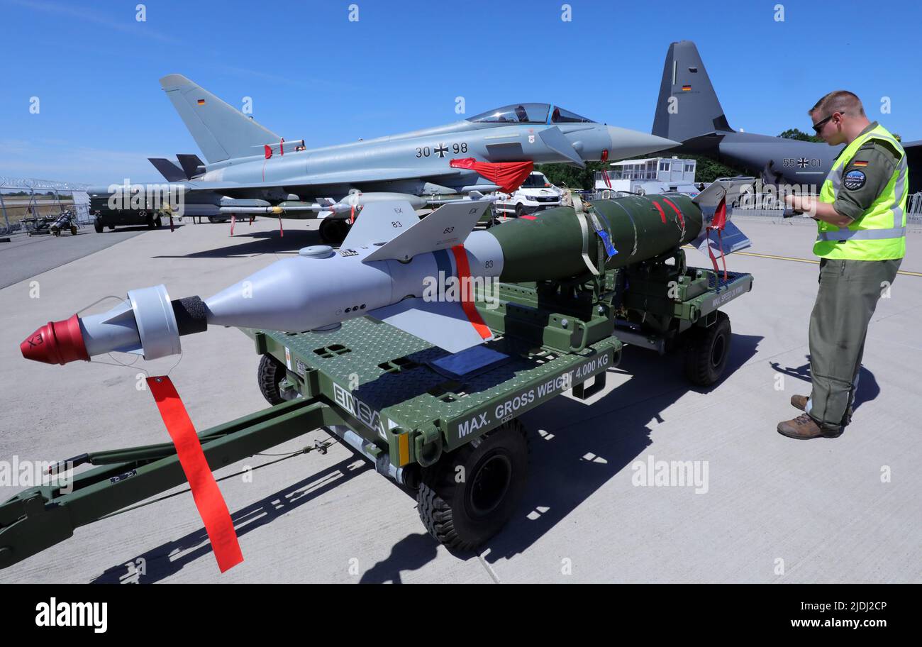 21 June 2022, Brandenburg, Schönefeld: A mechanic from the German Air Force  checks a GBU-48 glide bomb suspended under the wings of a Eurofighter (in  the background) at the ILA International Aerospace