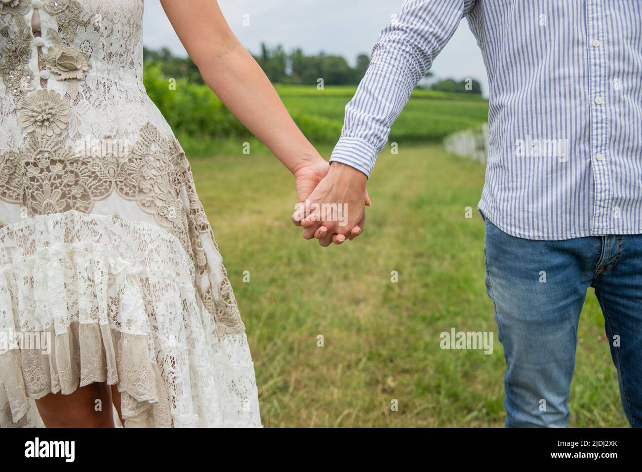 Close-up of the hands of a couple holding hands outside in a vineyard Stock Photo