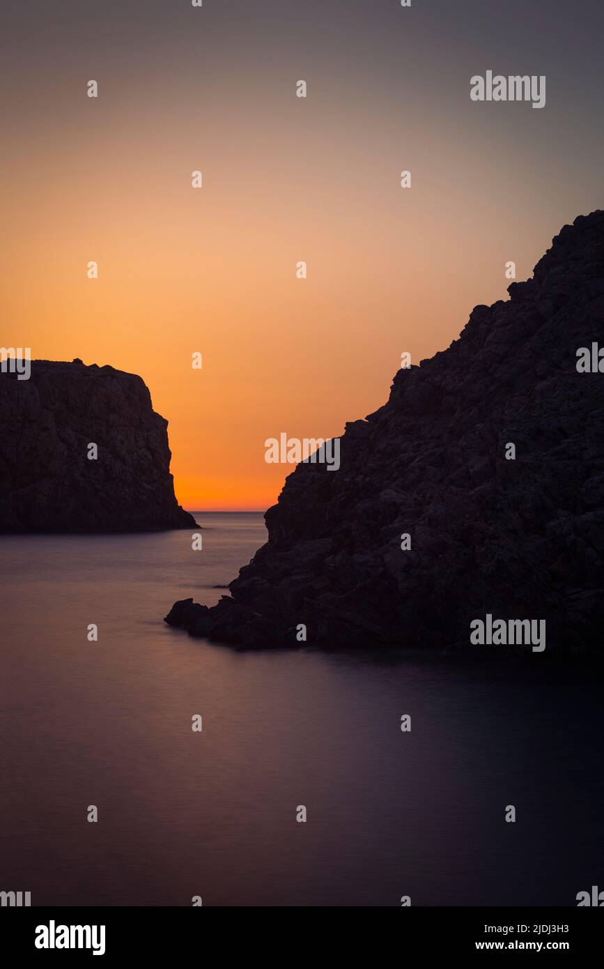 Sky glowing golden at dusk in the fjord-like bay of Cala Domestica in the southwest of Sardinia, Iglesiente, Italy Stock Photo