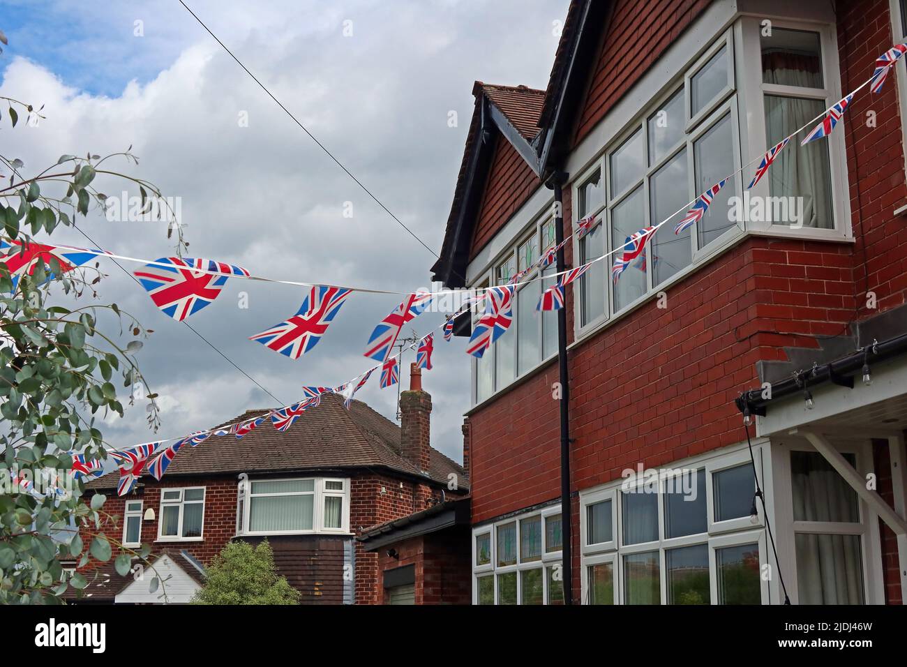 English patriotism in Grappenhall village, Kings coronation and national events - Union flags and bunting flying across suburban St, Warrington, UK Stock Photo