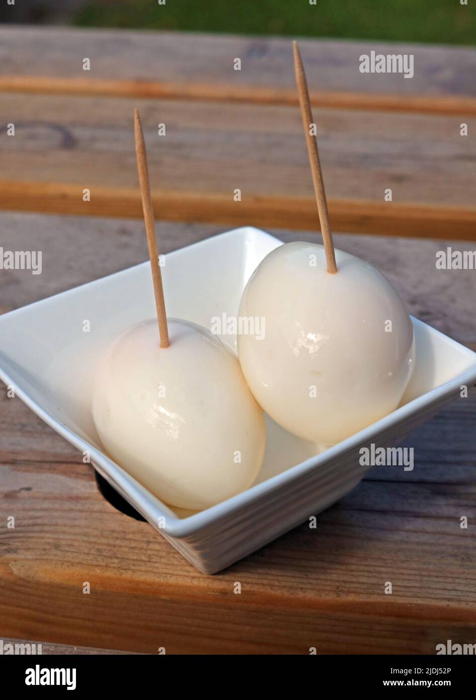 Two malt vinegar pickled eggs on a British pub table, a tasty snack with beer in a British pub beer garden, eaten using a cocktail stick Stock Photo