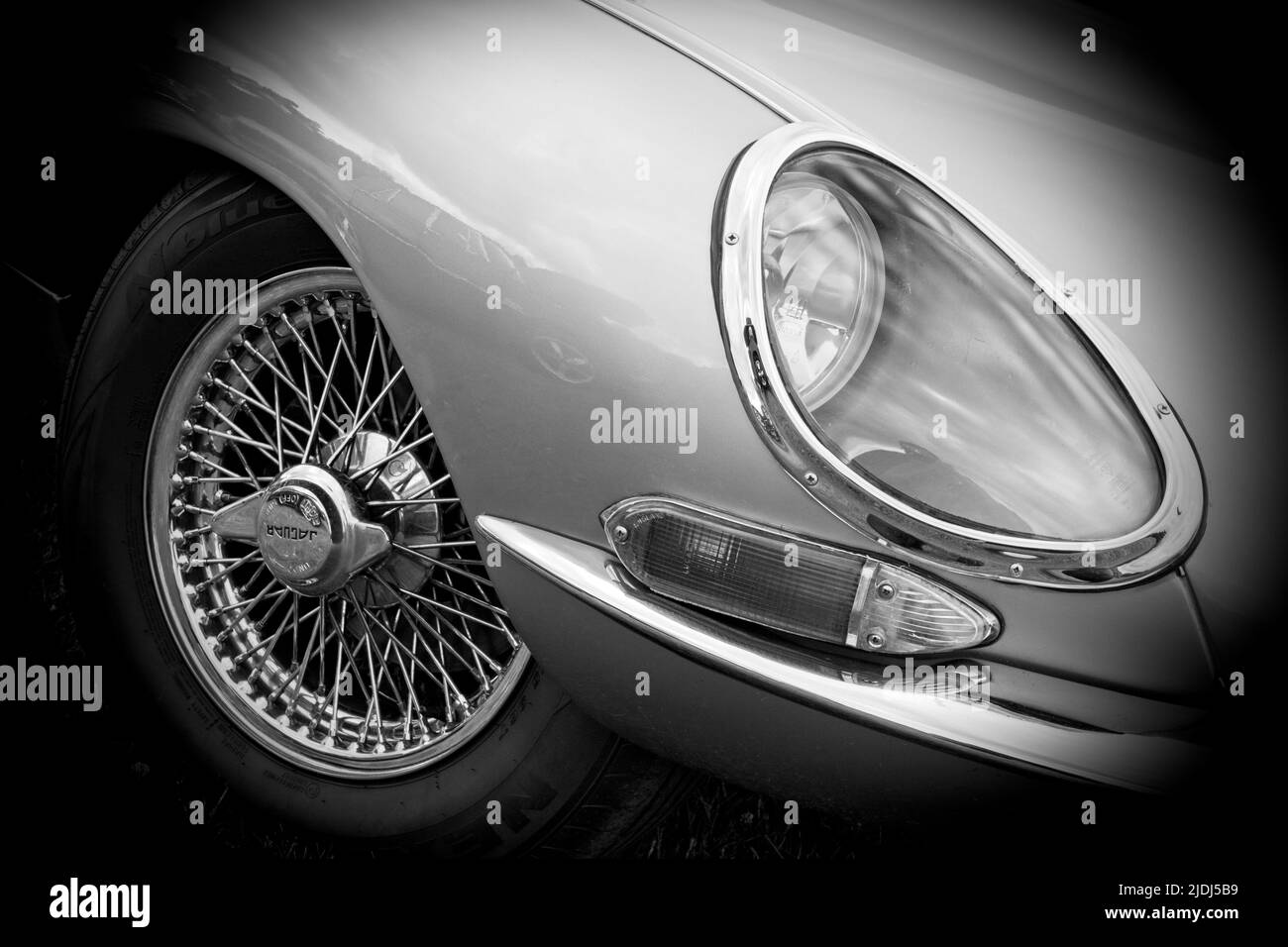 Front headlight of a classic vintage Jaguar E-Type from the 1970's presented in black and white. Stock Photo