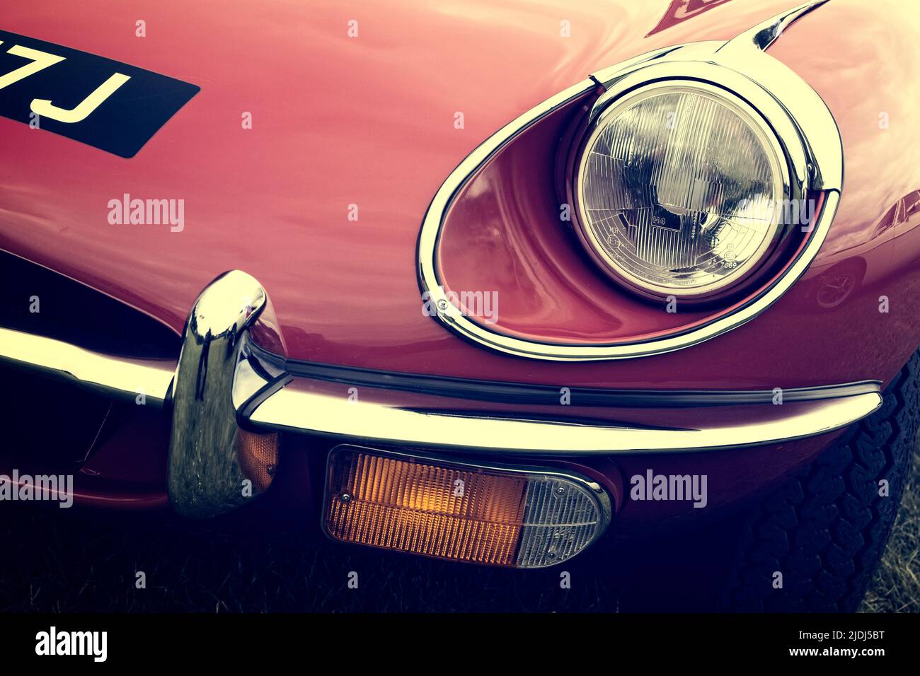 Front headlight detail of a classic vintage red E-Type Jaguar motor car from 1970. Stock Photo