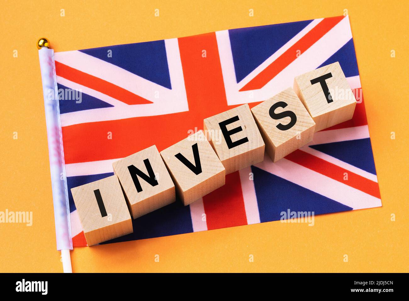 Wooden cubes with text and a flag on a colored background, the concept of investment from UK Stock Photo