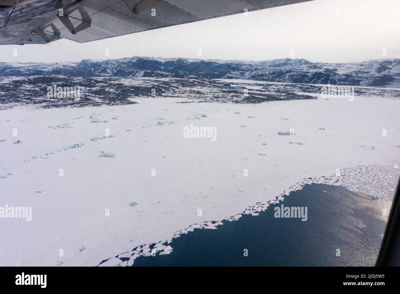 flying tour above Greenland with Icebergs floating on the ocean Stock Photo