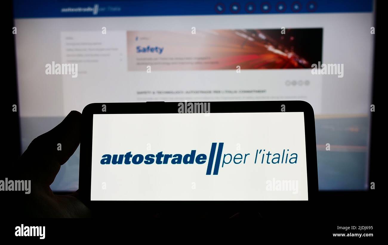 Person holding smartphone with logo of motorway company Autostrade per l'Italia S.p.A. on screen in front of website. Focus on phone display. Stock Photo