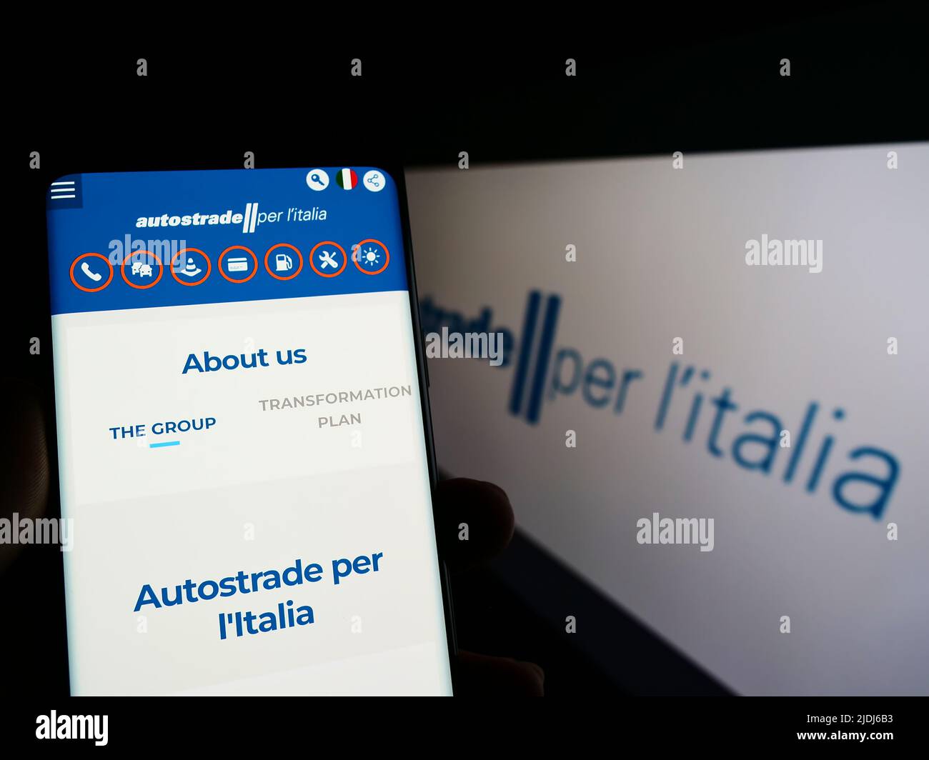 Person holding smartphone with website of motorway company Autostrade per l'Italia SpA on screen with logo. Focus on center of phone display. Stock Photo