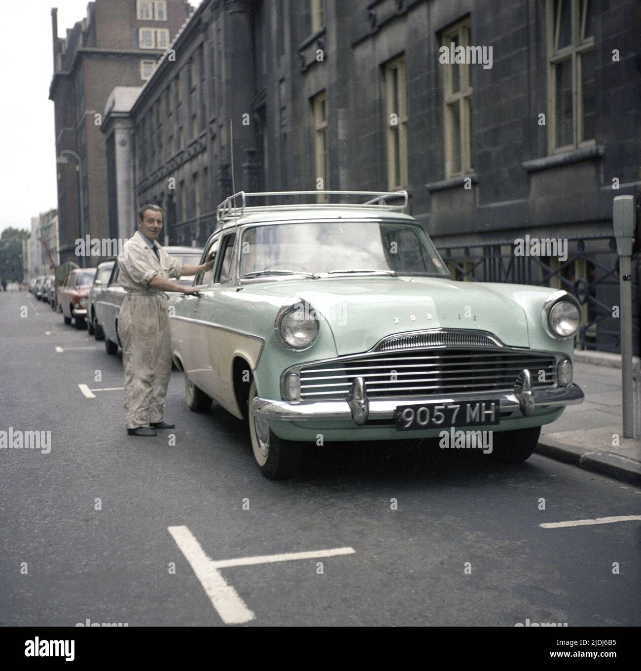 1964, historical, a man in his work overalls standing by his car of the era, a tone-tone, Ford Zodiac, parked in a street, England, UK Stock Photo