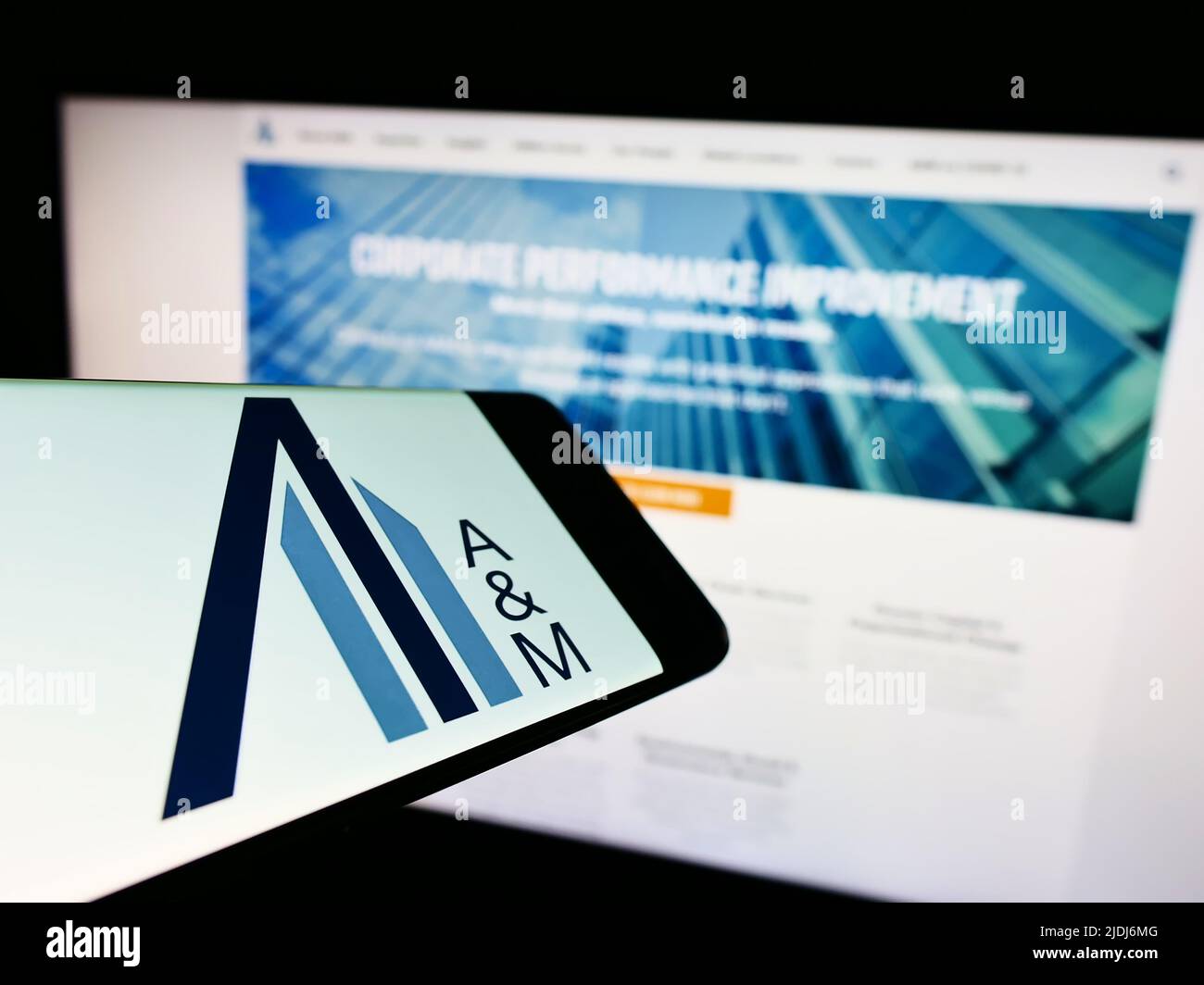 Cellphone with logo of American consulting company Alvarez and Marsal LLC on screen in front of website. Focus on center-right of phone display. Stock Photo
