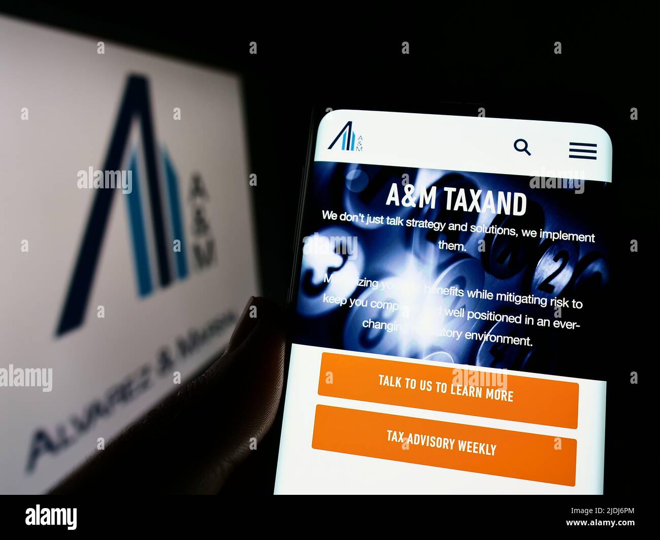 Person holding smartphone with webpage of US consulting company Alvarez and Marsal LLC on screen with logo. Focus on center of phone display. Stock Photo