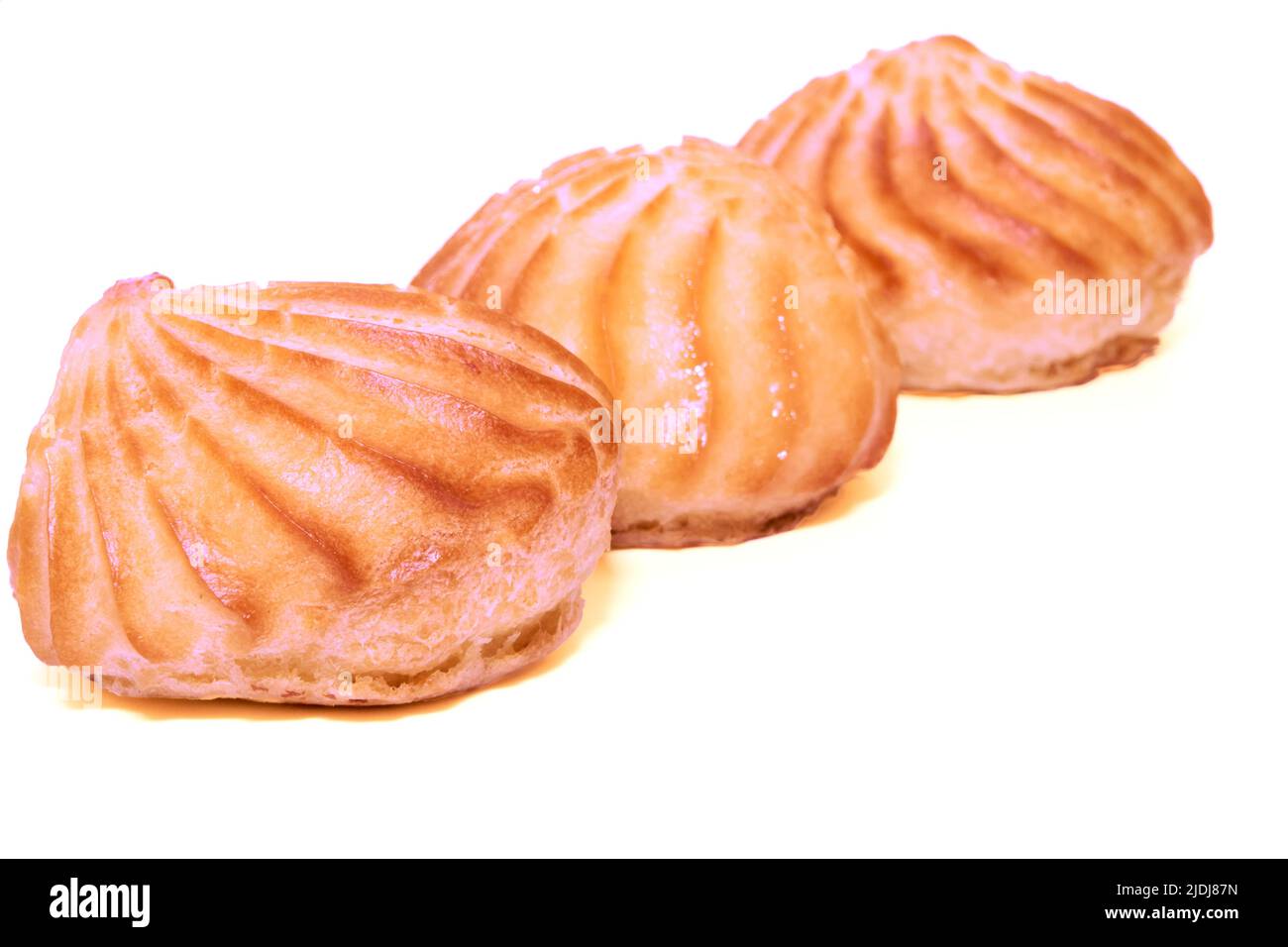 Three pink delicious appetizing profiterole eclair cakes on a white background Stock Photo