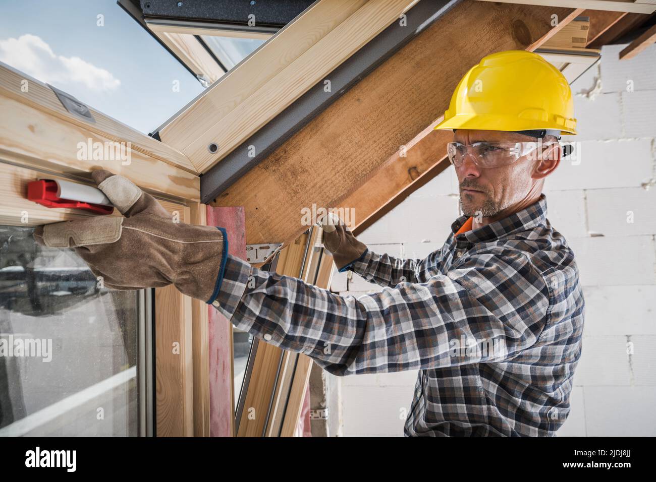 Professional Contractor Focused on His Work Testing the Functionality of Freshly Installed Roof Windows in a New Building Under Construction. Stock Photo