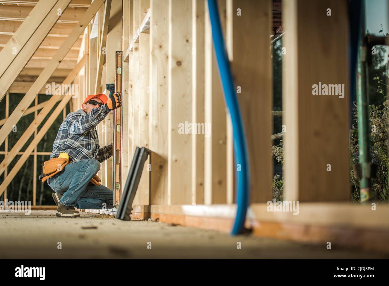 Process of Building New Wooden Residential Houses. Checking the Level of Building Carcass Walls with a Spirit Level Tool by Carpenter. Construction In Stock Photo