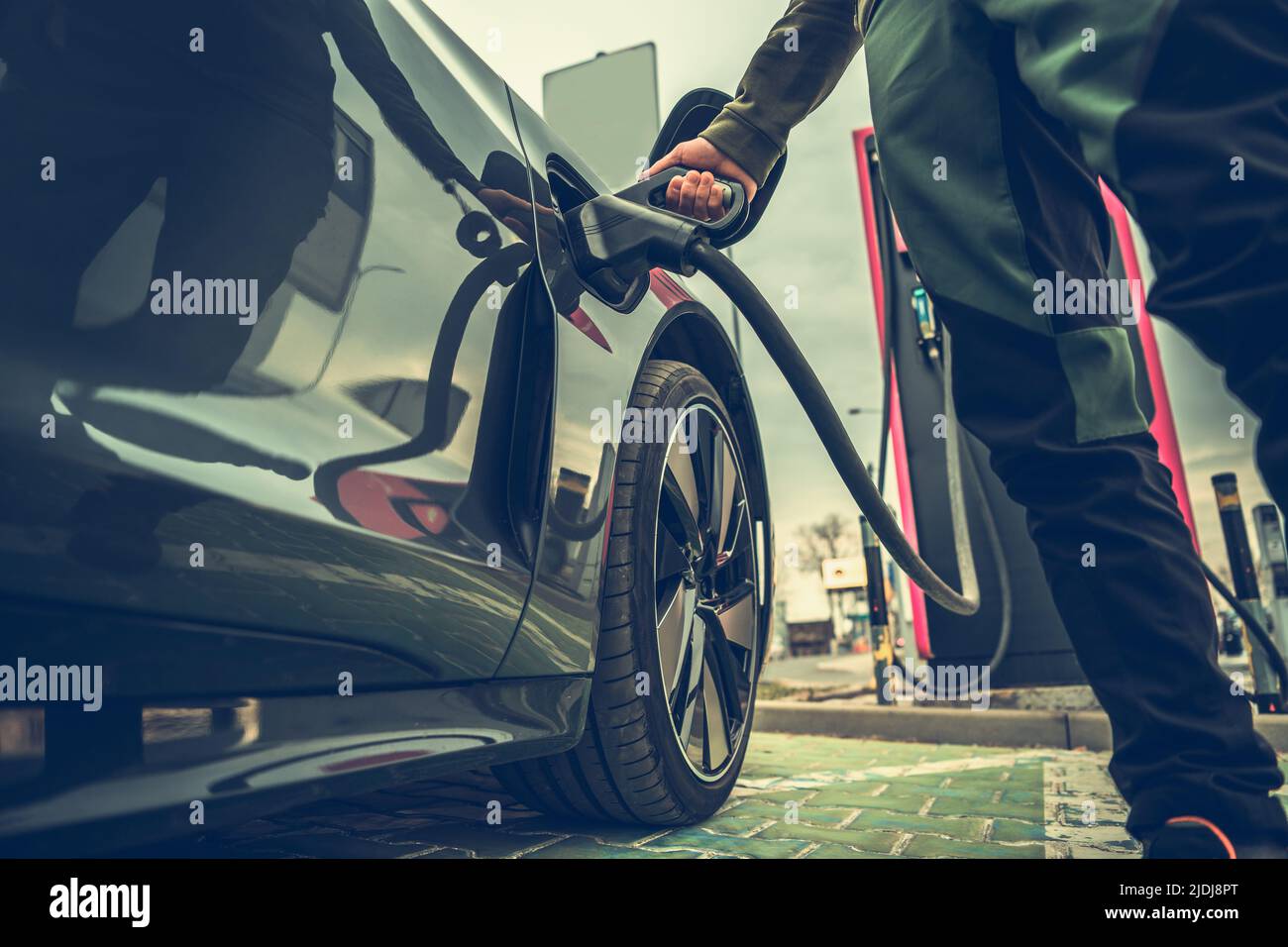 Electric Car Parked at a Special Fast Charging Station to Recharge the Batteries For Further Route. Driver Inserting the Charger Plug. Green Energy Th Stock Photo